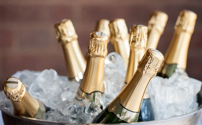 Several champagne bottles with gold foil tops are chilling in a bucket filled with ice.