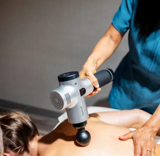 At Golf Resort & SPA The Westin Stonebriar, a person uses a handheld massage gun on another’s bare back during a relaxing therapy session.