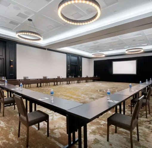Spacious conference room at Golf Resort & SPA The Westin Stonebriar PA with U-shaped tables, bottled water, and circular ceiling lights.